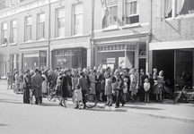 831649 Afbeelding van mensen in de rij voor (vermoedelijk) de voedseldistributie in de winkel in boter, kaas en eieren ...